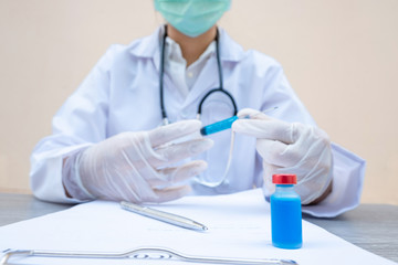 Fototapeta premium The picture of a blue serum tube on the table and a doctor