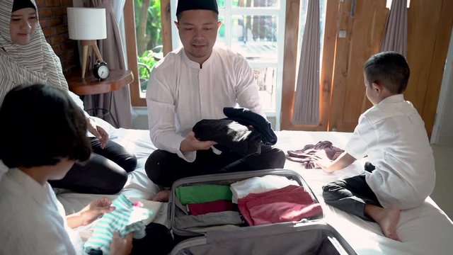 Father and her child prepare clothes and suitcase for carried when mudik go to the village