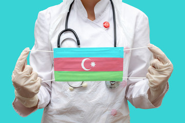 Epidemic in Azerbaijan. Young woman doctor in a medical coat (suit) and gloves holds a medical mask...