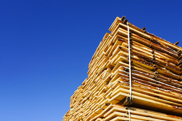 large stacks of wooden planks at the sawmill yard on the blue sky background