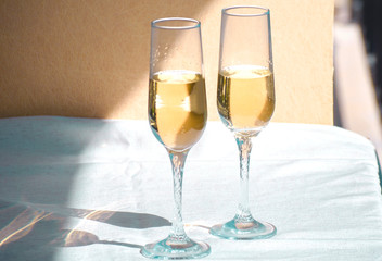 Two glasses of champagne. Glass goblets with alcohol on background of wooden wall. White linen tablecloth. Selective focus image. Copy space.