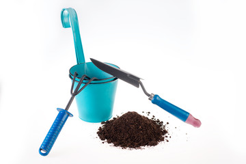 View of gardening tools on a white background. Rakes, spatula and brown pile of soil
