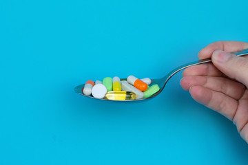 A lot of multicoored pharmaceutical medicine tablets, pills and capsules in spoon. Concept of...