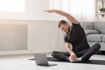 Young man practicing fitness with online training on laptop - Powered by Adobe