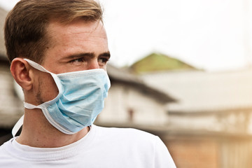 Young guy in a protective mask close-up. The guy in the medical mask adheres to the quarantine rules to prevent infection with a coronavirus infection. Self-isolating man during coronavirus quarantine