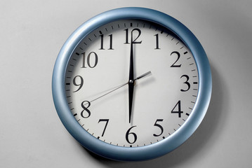 An analog wall clock displaying 6 o'clock.