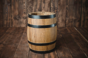 There is a wooden barrel on the background of brown boards.
