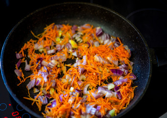 Onions and carrots in a pan.