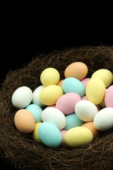 Pastel coloured easter eggs in nest with copy space