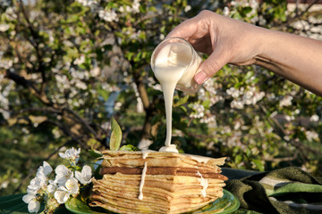 Delicious thin pancakes with creme on wooden table, flat lay. Homemade dessert. Shooting in garden outdoors. 
