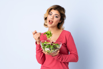 Teenager woman with salad isolated on blue background