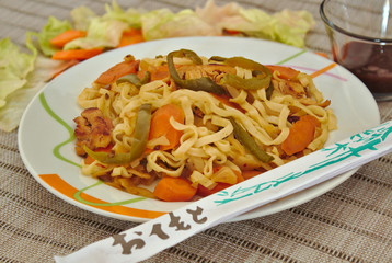 Side view of chinese food which include vegetables like carrots and lettuce with noodles, chicken and soya sauce.