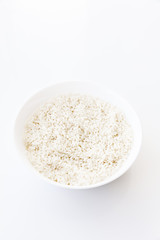 Raw dry rice in bowl isolated on white background, top view. Main asian food ingredient, natural food high in protein
