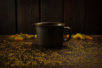 a saucepan on a background of pasta, seeds and wood