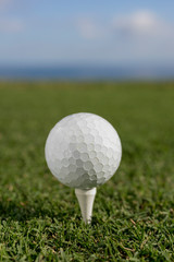 closeup of a golf ball with grass and sky background