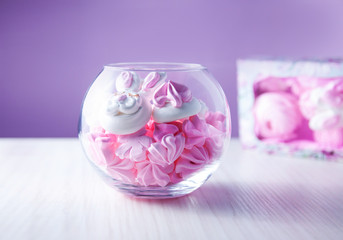 sweet meringues in a glass jar on a purple background