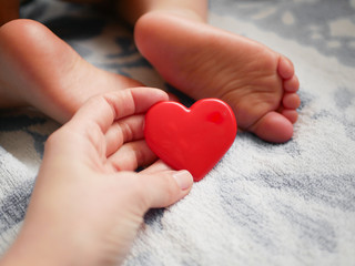 mother holds heart on the background of a small child