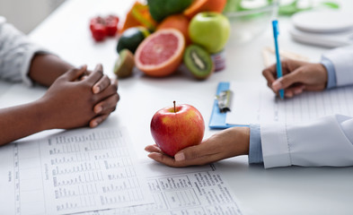 Close up of dietologist and patient hands over doctor workplace