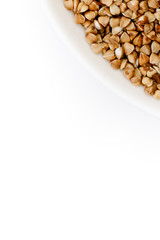 Bowl of uncooked buckwheat grains on white isolated background