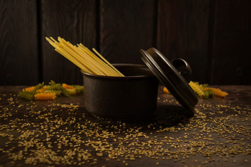 pasta in a semi-open brown saucepan with a bottom yogurt and seeds on a wooden background