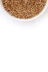 Bowl of uncooked buckwheat grains on white isolated background