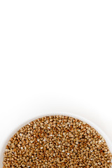 Bowl of uncooked buckwheat grains on white isolated background