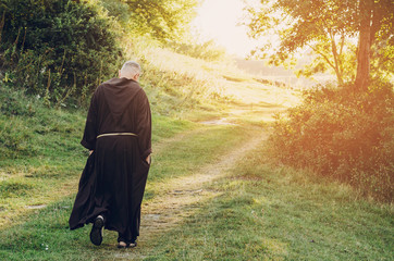 monk of the Capuchin Order, an adult wise man with a beard and in long dark brown clothing walks...