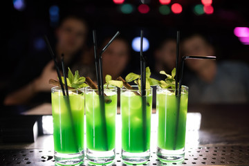 Fresh mojito cocktail with lime, rosemary, mint and ice in a glass glass on a black background. Summer cold drink and cocktail.nightclub life