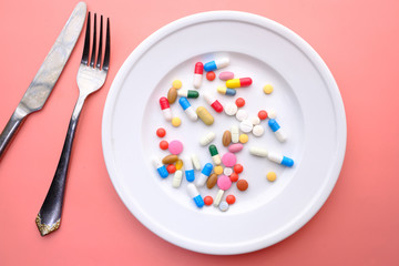 Top view of colourful medicine pills and capsules in plate.