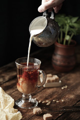 coffee with cream in a rustic style, milk pours into a glass
