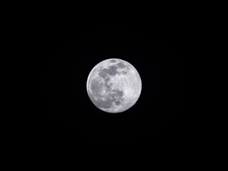 Close up vivid photograph of a full moon worm moon or sap moon supermoon centered on a black night sky background showing craters and detailed texture of the moon surface.
