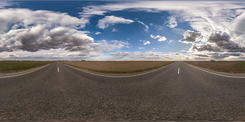 Full spherical seamless panorama 360 degrees angle view on no traffic asphalt road among fields in evening  before sunset with cloudy sky. 360 panorama in equirectangular projection, VR AR content