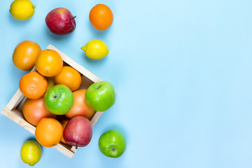 fruit lemon, apples, oranges in wooden box on a blue background. zero waste concept. No plastic.