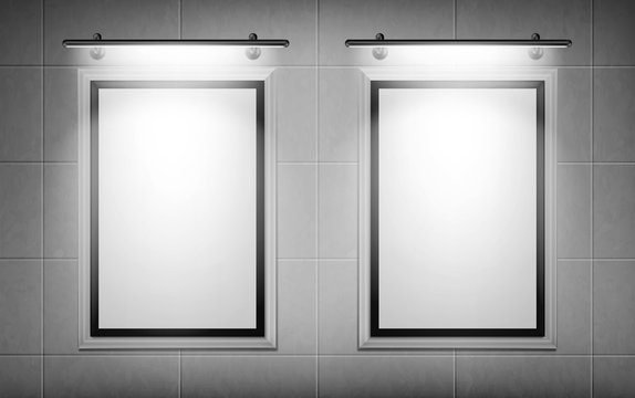 Blank movie posters illuminated by spotlights. Vector realistic mockup of white picture frames on gray tiled wall in cinema, theater or gallery. Empty advertising banners with black border and lamps