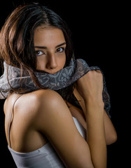 Portrait of beautiful young woman with white scarf on black background