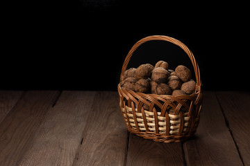 Nuts in a straw woven basket on a wooden table.