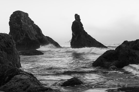 Black and white image of waves splashing on sea stacks at Bandon beach in Oregon