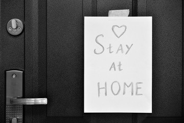 Stay at home - inscription on a paper sheet on the entrance door to the house, the concept of COVID-19 and coronavirus