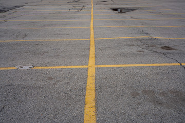parking lot on asphalt with yellow marked parking lines and old cracked pavement 