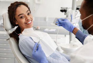 Pretty black woman in dentist chair ready for check up