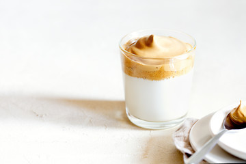 Trendy fluffy creamy whipped iced Dalgona coffee on white background.Korean drink latte espresso with foam of instant coffee.Horizontal orientation,copy space