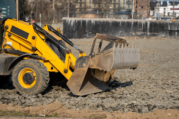 Yellow wheel loader Excavator machine working at construction site with a sand and gravel. Preparing of the fundament for a asphalting. Road construction site. Building of a parking.