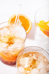 Cold brew coffee mocktail with orange peel and glass straw close-up.Glass with citrus espresso tonic on white background close-up.Refreshing summer non-alcoholic drink concept.Vertical orientation
