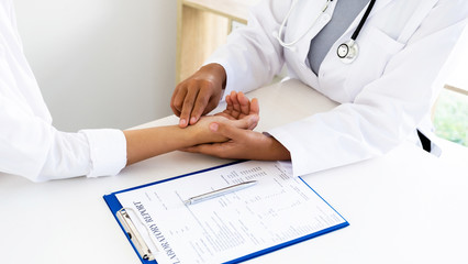 The doctor examines the patient's pulse by hand and records the results, health medical checkup concept