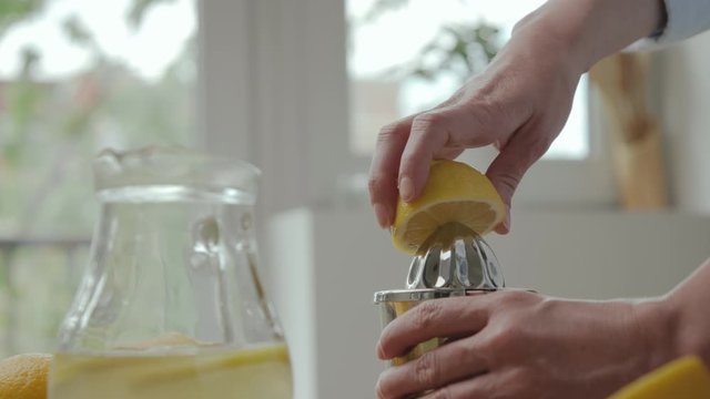 Close up of woman's hand squeezing lemon. Woman making homemade lemonade.