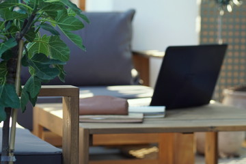 view of a cozy outdoor workplace with a laptop on a table of a sitting area