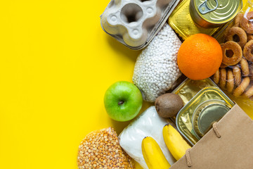 Healthy food on a yellow background. Food delivery in eco bag. Food donations. Flat lay style. Copy space for text.