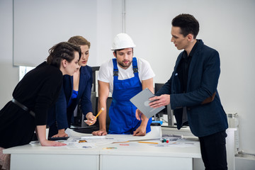 A team of constructions designers meeting with an engineer in the office to discuss the current project. Cooperation concept