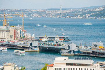 Top view of Galata bridge, Golden Horn, Bosphorus in background. White pleasure ships. Seagulls flying over water. popular tourist destination. Red tiled roofs. Turkey, Istanbul