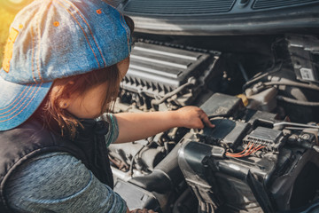 Little child trying to fix broken real car. Dreaming to be auto technician. View from the back